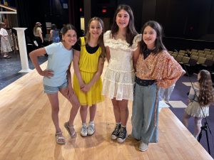 four young girls stand  on a theatrical stage