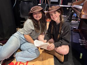 two girls sit on a stage