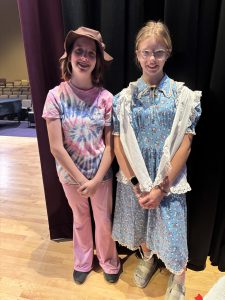 two girls in theatrical costume pose on a stage