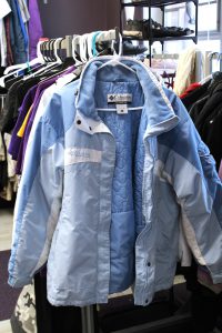 a blue winter coat hangs on a rack