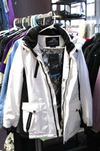 a white winter coat hangs on a rack