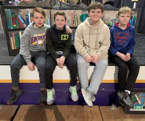 four students sit on a theatrical stage