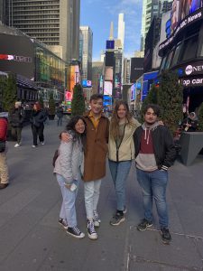 four teenagers pose in the middle of a busy city intersection