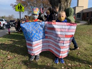 two students stand outside holding a handcrafted American flag