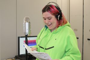 a high school wearing headphones student sings in a mock recording studio in a high school classroom