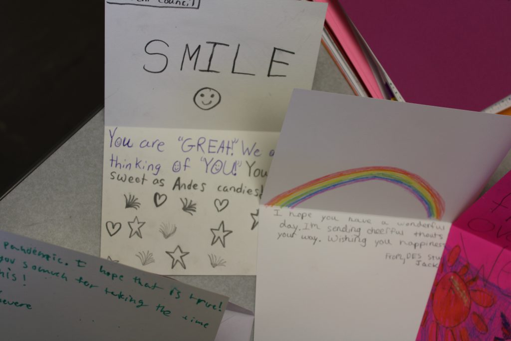 handwritten card says "Smile" with a smiley face next to a card with a hand drawn rainbow