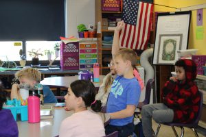 young students listen to a presenter in a classroom