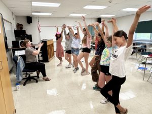 a group of young female students strike a pose as part of a theatrical rehearsal