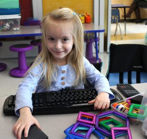 a young girl with blonde hair types on a keyboard