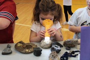 a young girl looks through a microscope into a rock