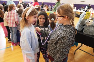 two girls test out a stethoscope on each other