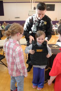 a young girl tries on a sheriff's vest