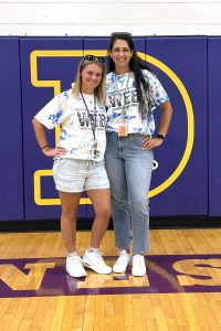 two adult females pose together in a gymnasium
