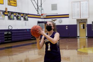 a young basketball player wearing a purple number one jersey takes a shot on basket