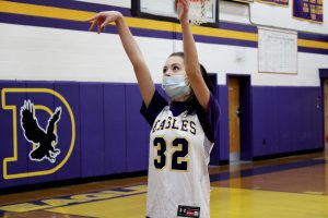 a basketball player wearing a white number 32 jersey throws a basketball at a hoop