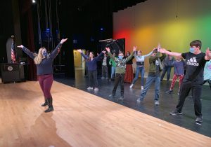 a woman stands in front of a group of students to show them choreography moves