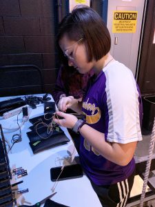 a student works on microphones backstage in a theater