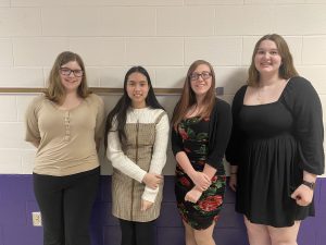 four female teenage students pose in a hallway