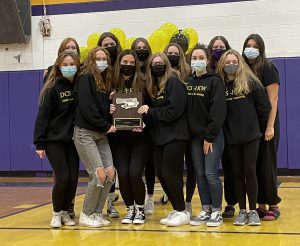 a group of young females wearing face masks hold a plaque while posing inside of a gymnasium