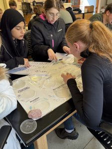 young female teen students use microscopes in a classroom