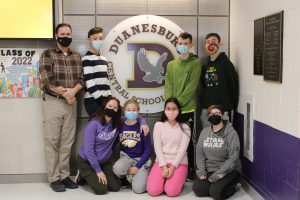 a group of students pose with their teacher in front of the DCS school logo