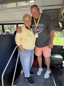 a woman and a man pose together on board a school bus
