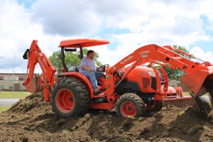 a man uses an orange tractor on a pile of dirt