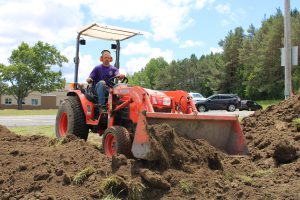 a man sits on a red tractor and moves a pile of dirt