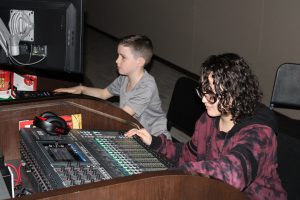 two students work on a sound board in a theater