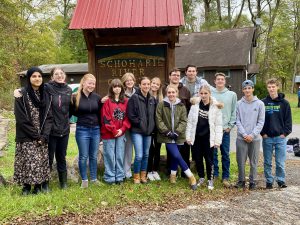 a group of teen students pose outside in front of a sign