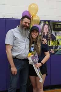 a man with a beard poses with an athlete on his team