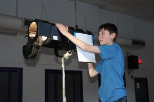 a young man uses a spotlight during play rehearsal