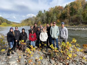 students stand on the banks of a river