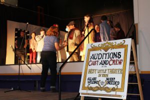 a play director gives directions to young students on a stage