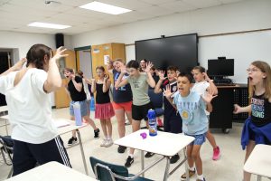 a group of young students rehears a scene where they have to practice a funny face