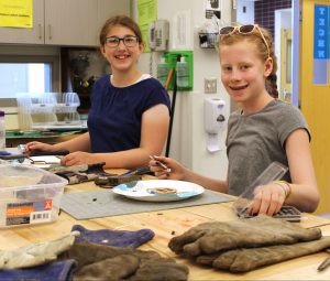 two female students sit at a work table to finish a project