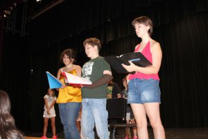 three teenaged student actors rehearse on a stage
