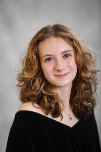 a girl with curly hair poses for a senior photo