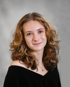 a classic senior portrait of a young girl with curly hair wearing a black top
