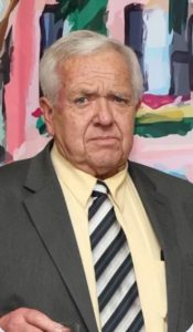 a man wearing a suit and tie stands in front of a colorful painting