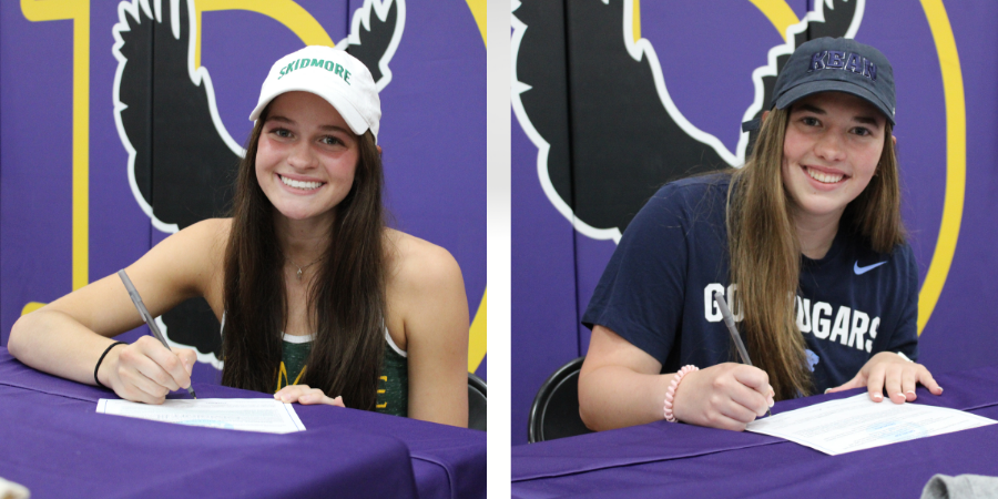 two young women wearing baseball caps smile as they sign a piece of paper