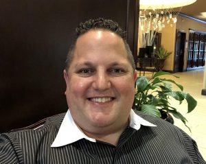 a man with dark hair is wearing a black button down shirt with a white collar