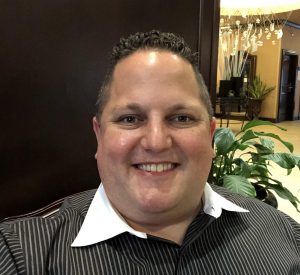 a man with dark hair is wearing a black button down shirt with a white collar