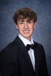 a young man with dark hair poses in a tuxedo