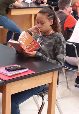 seated girl reading the book "Restart"