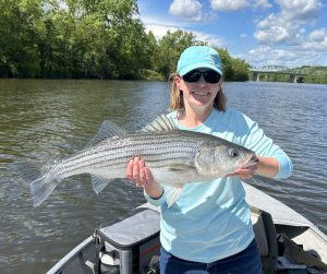 a woman in a boat holds a fish