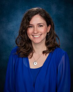 a woman with a blue shirt and dark hair sits for a posed photo