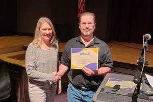 a woman shakes the hand of a man who is holding a certificate