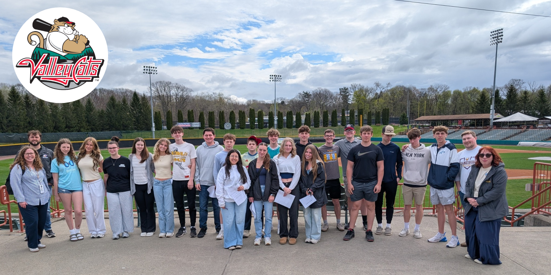 students pose outside of a baseball field