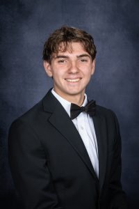 a young man with black hair wears a suit and bowtie for a posed photo